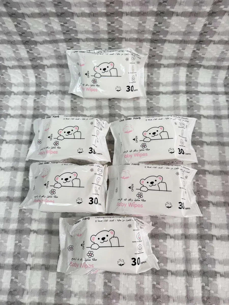 Pięć białych opakowań chusteczek nawilżanych Baby Wipes z nadrukiem misia i liczbą 30 sztuk na szarym tle
