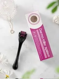 Derma Roller z czarną rączką i różowymi igłami obok różowego opakowania na jasnym tle