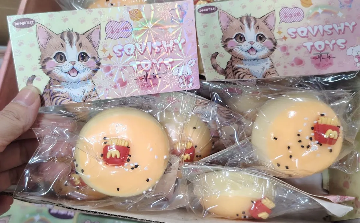 pomarańczowa miękka zabawka squishy hamburger z frytkami w przezroczystym opakowaniu z grafiką kota