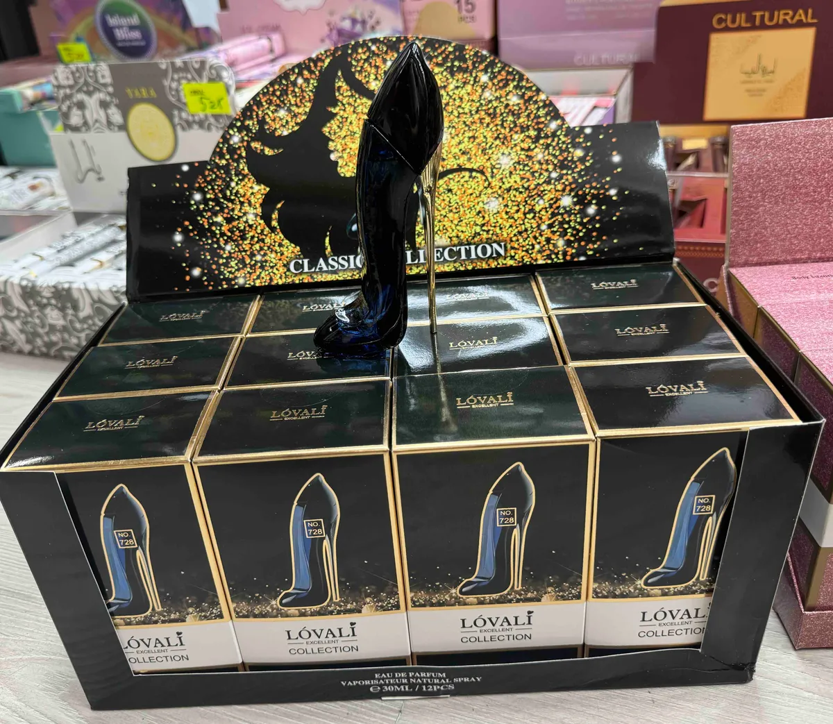 Perfum LÓVALI w flakonie szpilce granatowo-czarnym z czarną górą i złotym obcasem na ekspozycji