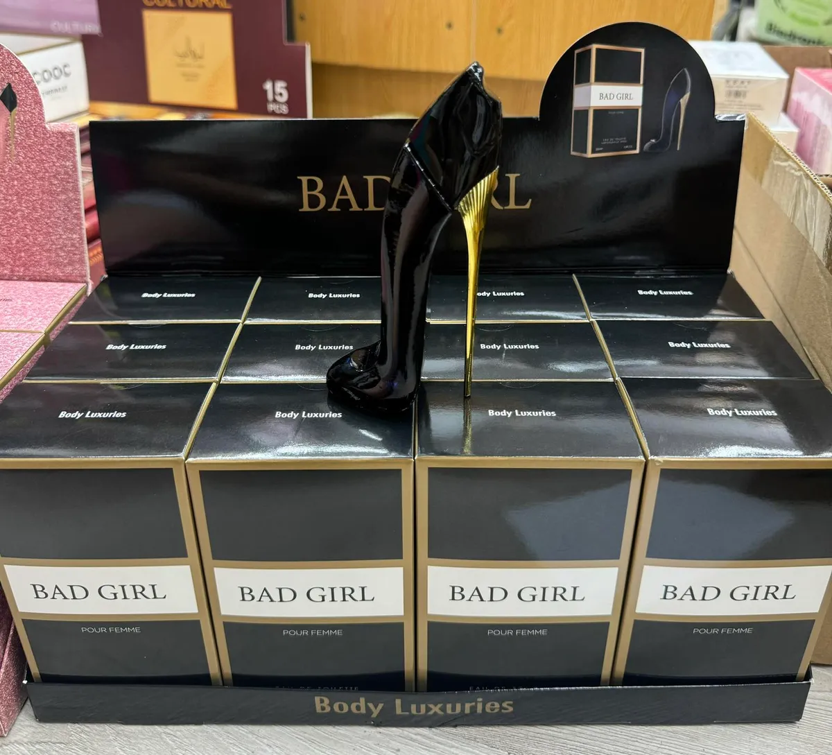 Perfum Bad Girl w czarnym flakonie szpilce z złotym obcasem na tle pudełek