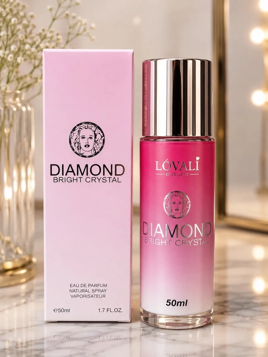 Butelka perfum Lövali Diamond Bright Crystal 50ml w odcieniach różu z srebrnym atomizerem obok różowego pudełka na marmurowym
