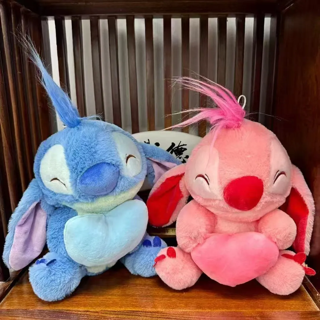 Dwie pluszowe maskotki Stitch i Angel w kolorze niebieskim i różowym, siedzące na drewnianej półce, wysokość 30 cm