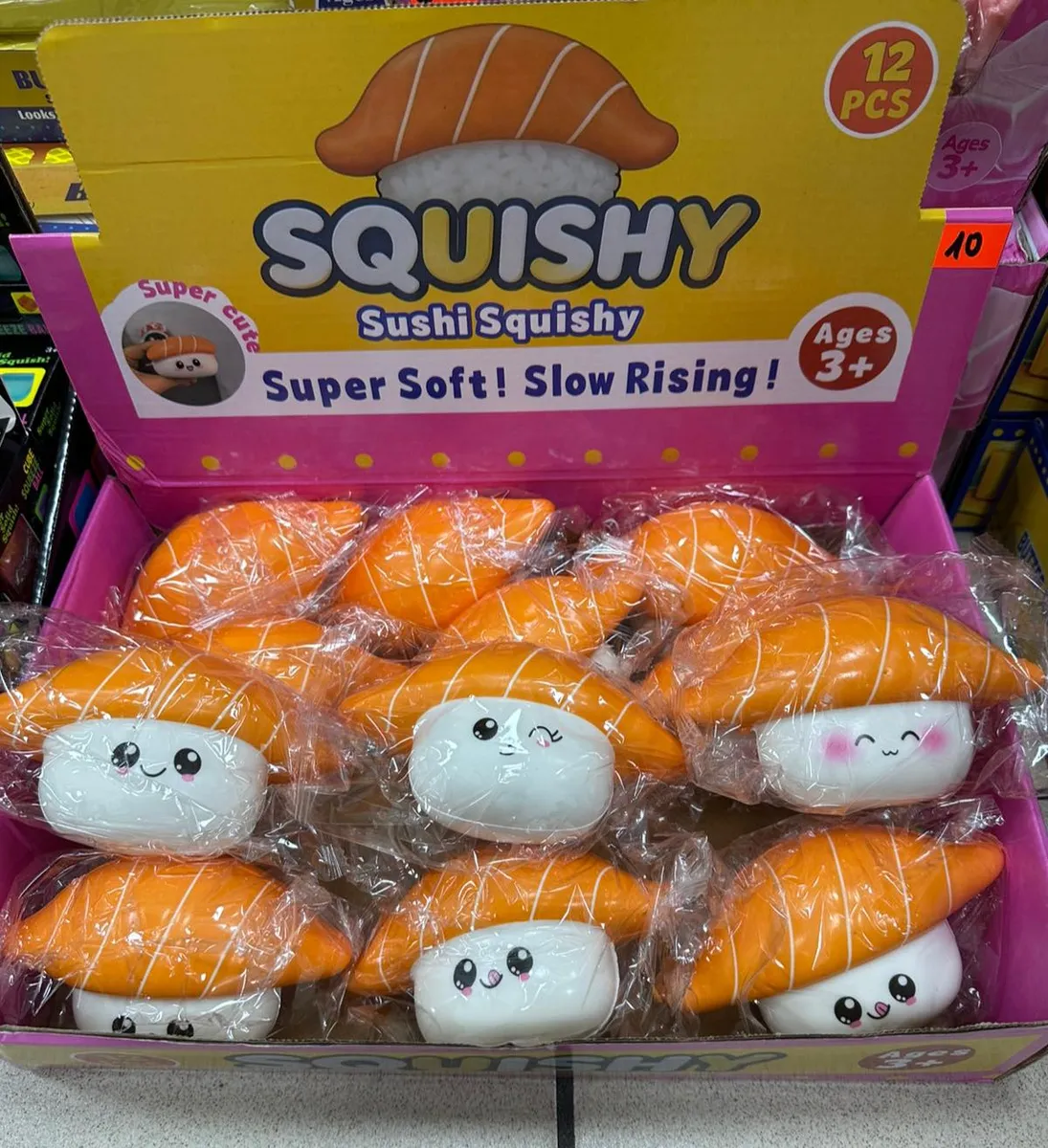 Zestaw 12 squishy w kształcie sushi nigiri z białym ryżem i pomarańczowym wierzchem, zapakowane w folię, w kolorowym displayu