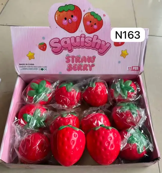 Otwarty karton z 12 zapakowanymi w folię czerwonymi squishy w kształcie truskawek z zielonymi listkami, różowe opakowanie z n