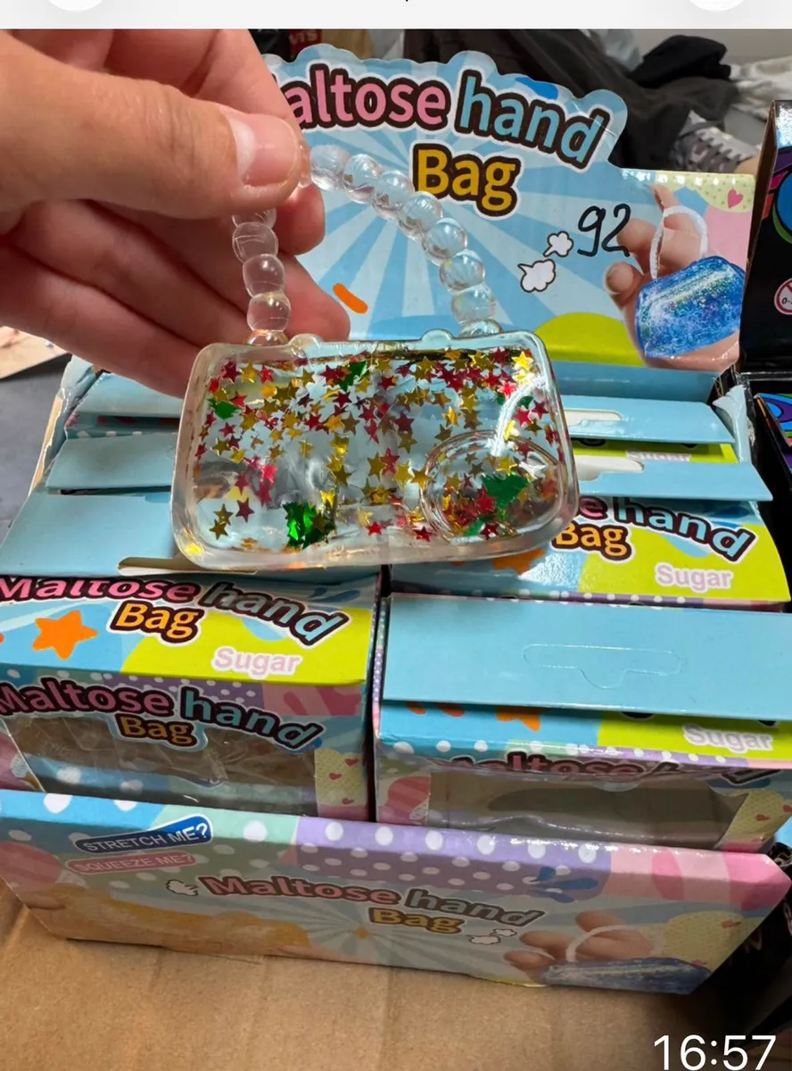 Ręka trzyma przezroczystą torebkę Maltose Hand Bag Sugar wypełnioną kolorowymi brokatowymi gwiazdkami z uchwytem z koralików