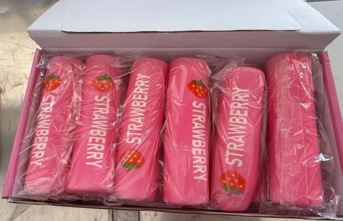 Sześć różowych piórników z nadrukiem STRAWBERRY i truskawką zapakowanych w folię, ułożonych w kartonie