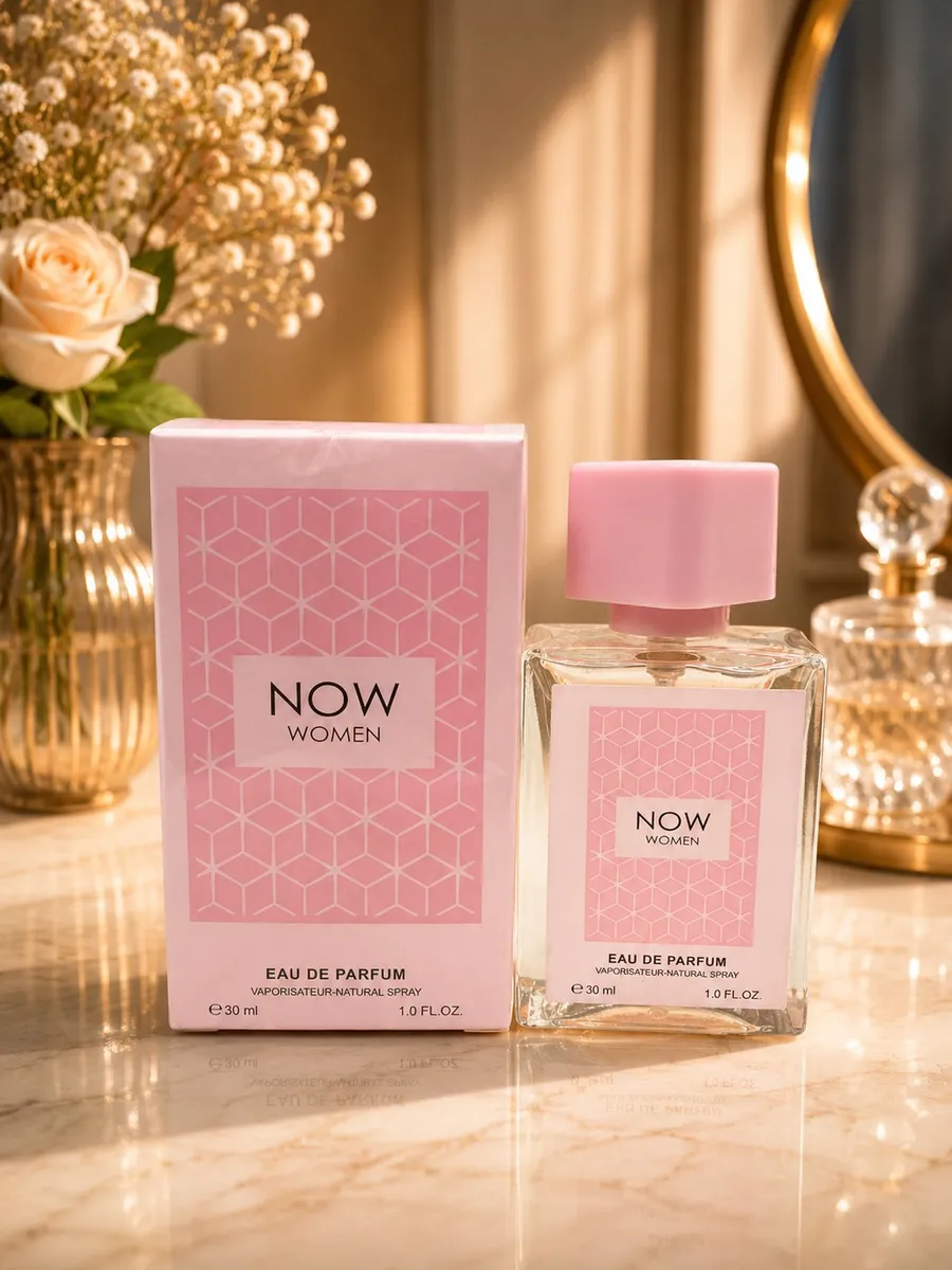 Szklany flakon perfum Now Women 30ml z pudrowo-różową nakrętką obok różowego kartonika na marmurowym blacie