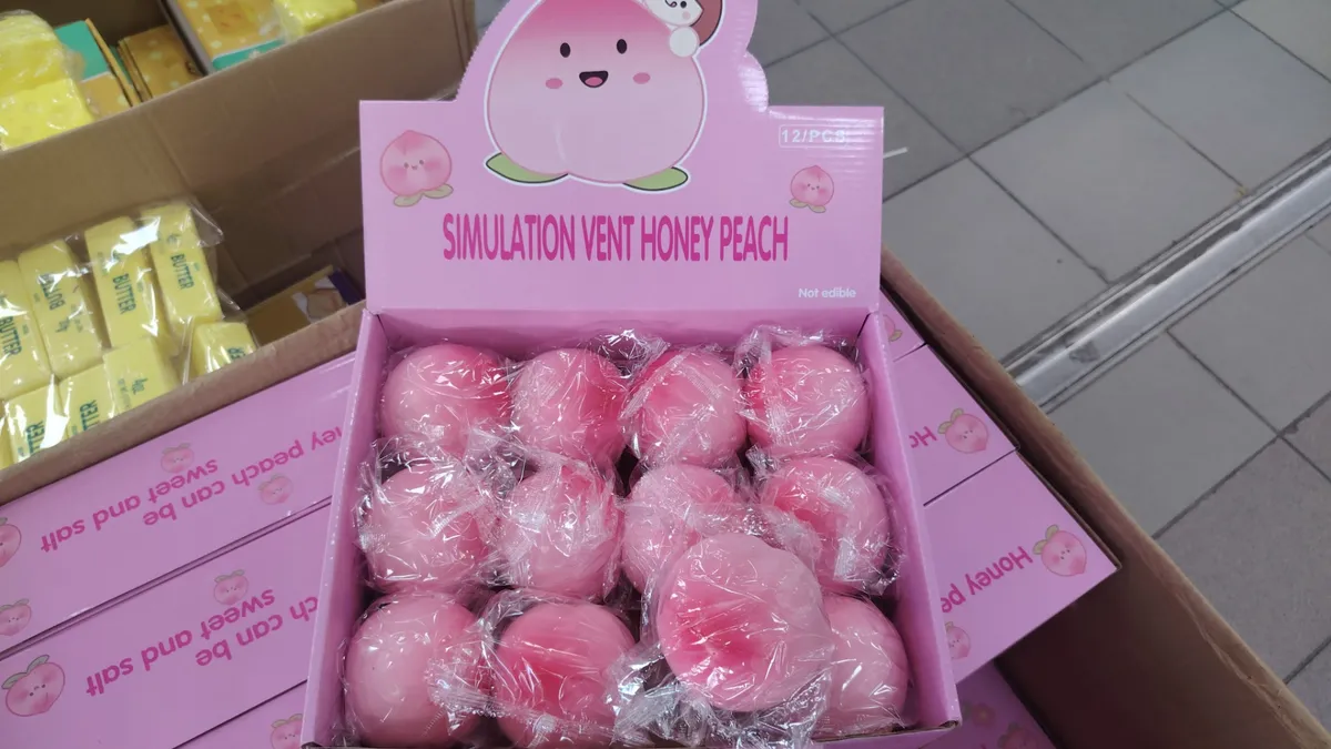 Różowe symulowane brzoskwinie Honey Peach zapakowane w folię, ułożone w różowym kartoniku z nadrukiem owocowego motywu