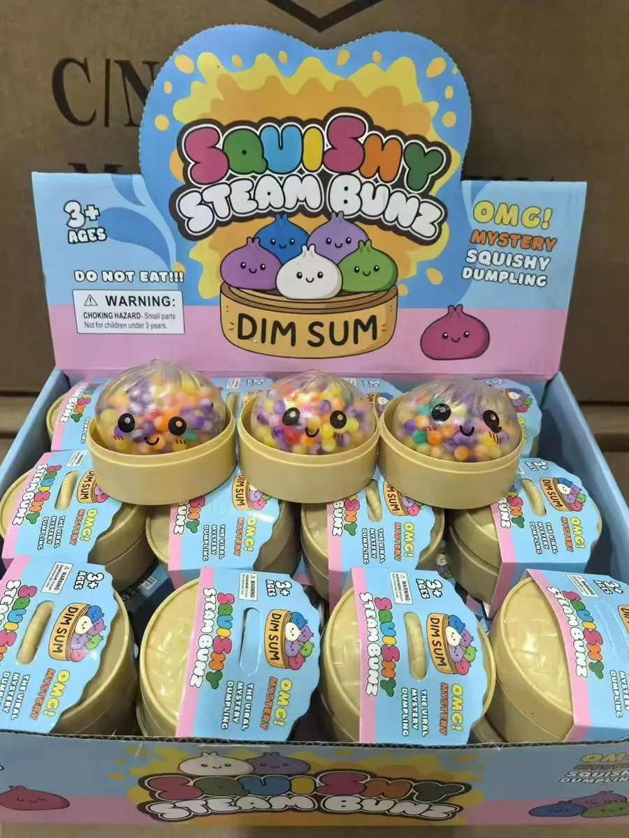 Zestaw squishy Steam Bunz Dim Sum w beżowych pojemniczkach z przezroczystą kopułką wypełnioną kolorowymi pomponami i uśmiechn
