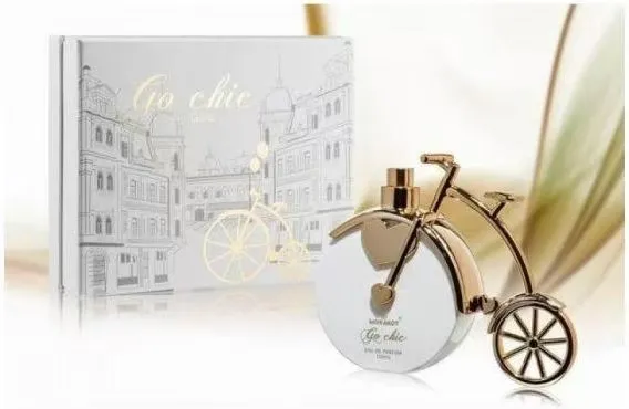 Perfumy Gio Chic w butelce w kształcie złotego roweru z białym opakowaniem z nadrukiem miasta