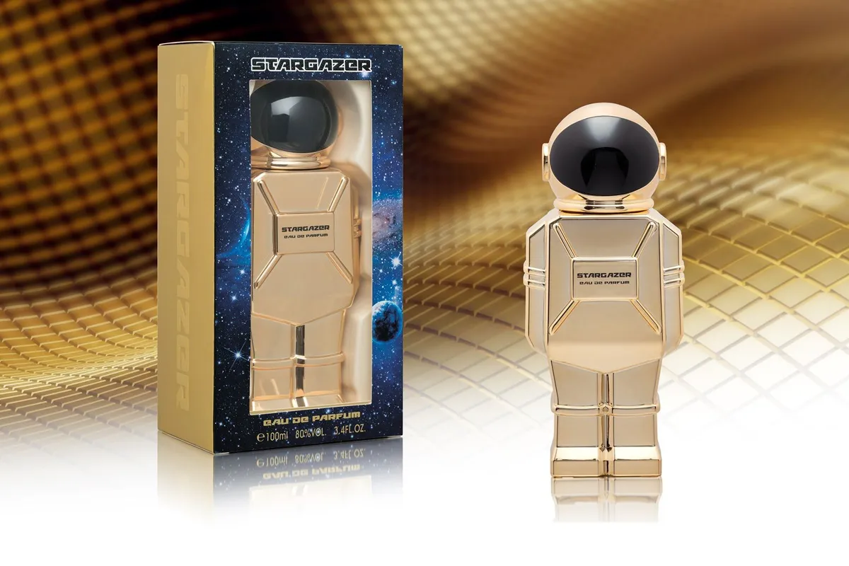 Złoty flakon perfum w kształcie astronauty z czarną przyłbicą i opakowanie z motywem kosmicznym