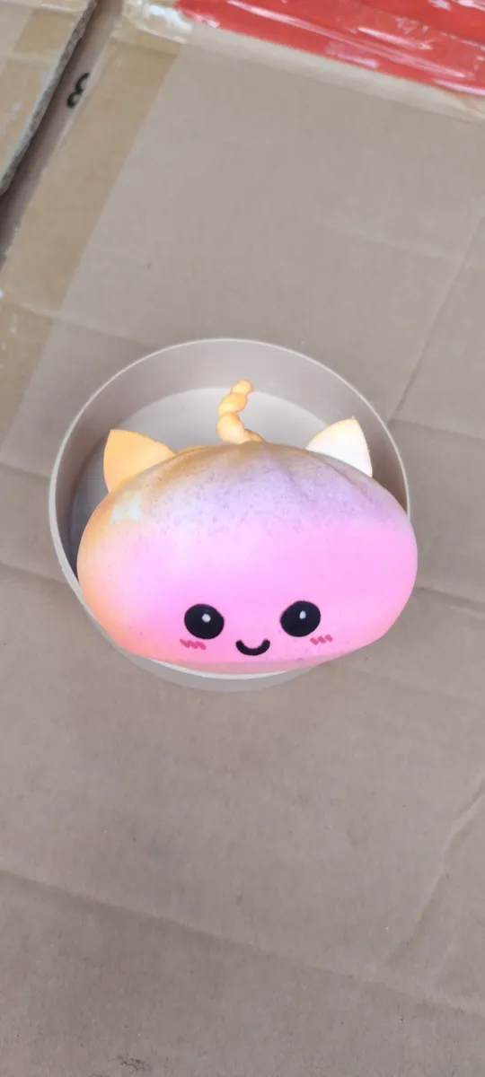 miękka zabawka squishy różowo-pomarańczowa z uszami i uśmiechniętą buzią w kartonowym opakowaniu