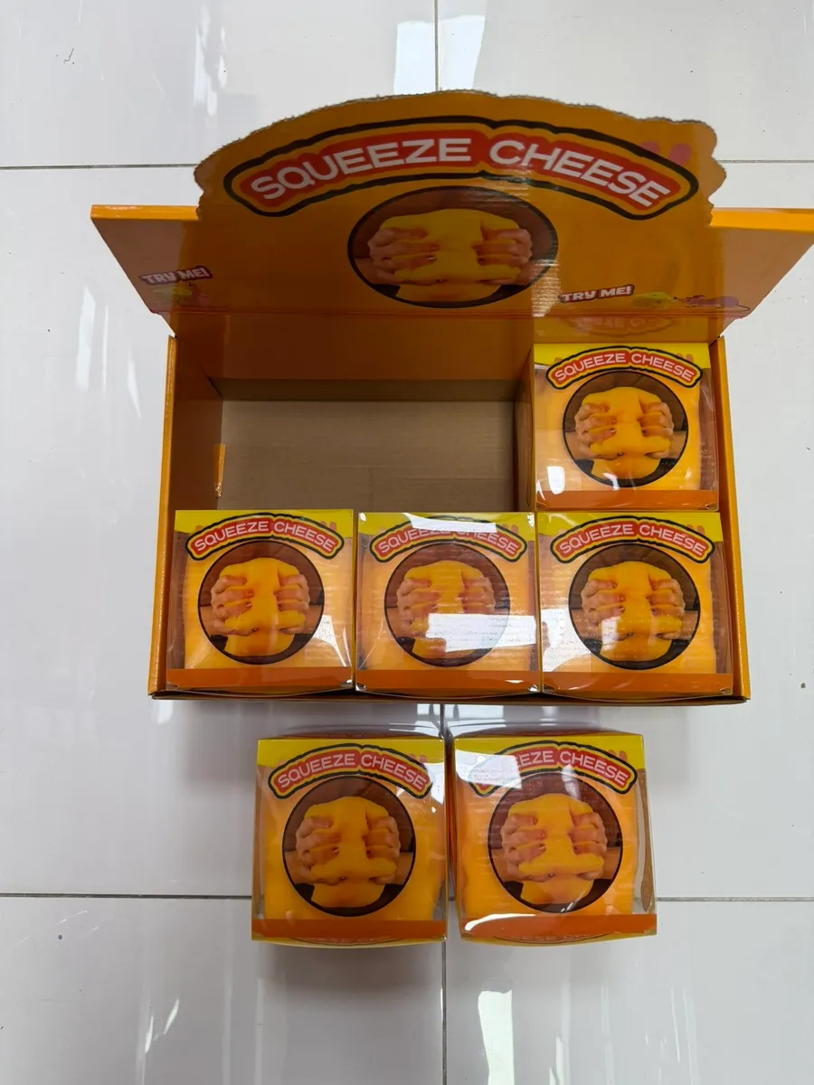Pomarańczowe gniotki antystresowe Squeeze Cheese w przezroczystych pudełkach na pomarańczowym displayu