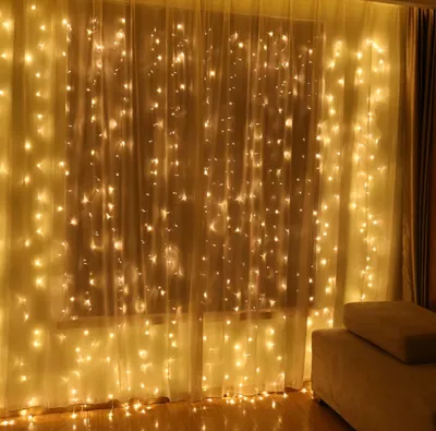 Lampa kurtyna LED 3m x 3m z ciepłym żółtym światłem dekorująca okno w salonie
