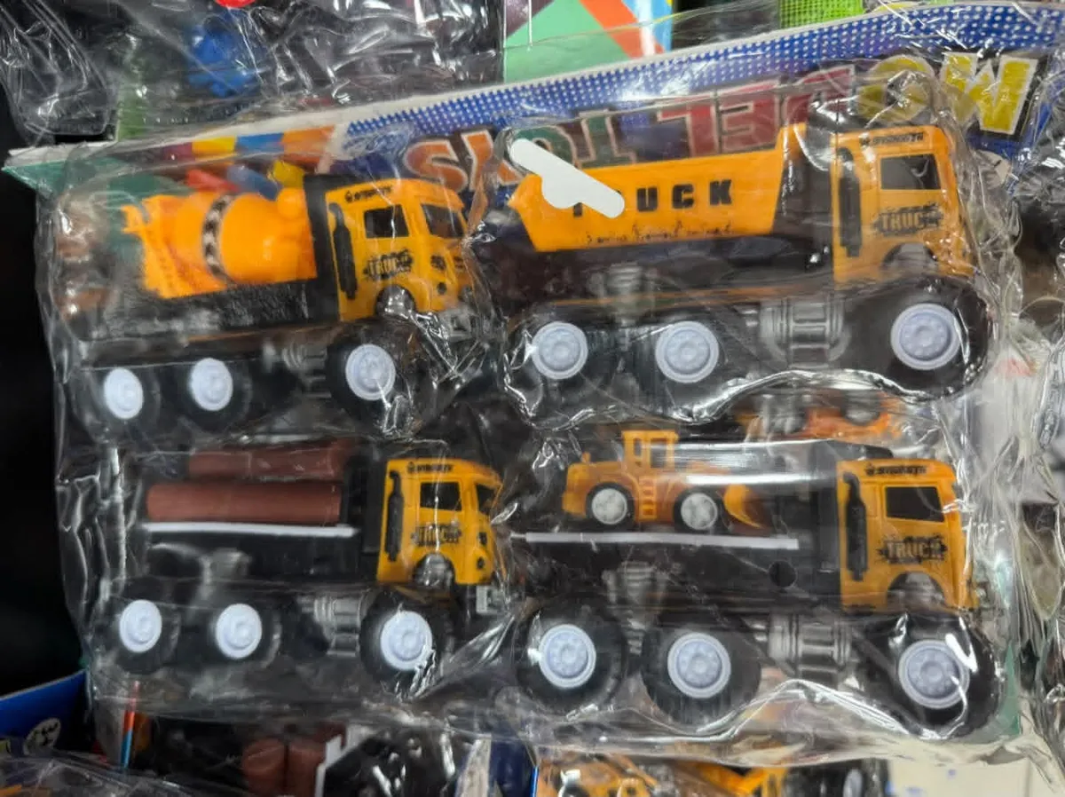 Zestaw czterech żółtych plastikowych ciężarówek budowlanych w opakowaniu foliowym