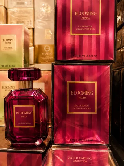 Różowy flakon perfum Blooming Passion 100ml z kartonikiem o pionowych paskach i złotych detalach