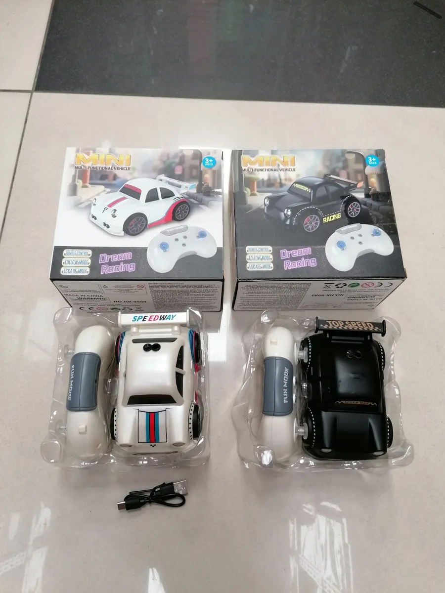Dwa mini samochody wyścigowe z pilotami i kablem USB, biały i czarny, w opakowaniach