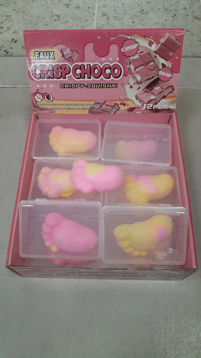 Zestaw 12 różowo-żółtych squishy w kształcie stópek w plastikowych pojemnikach na różowym tle opakowania