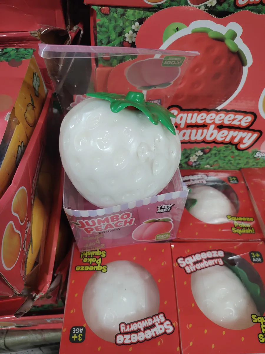 biały squishy w kształcie owocu brzoskwini z zielonymi liśćmi w opakowaniu