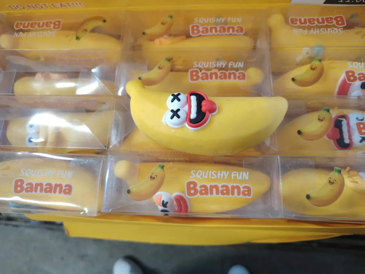 Żółta zabawka squeeze w kształcie banana z twarzą i opakowaniem z napisem Squishy Fun Banana