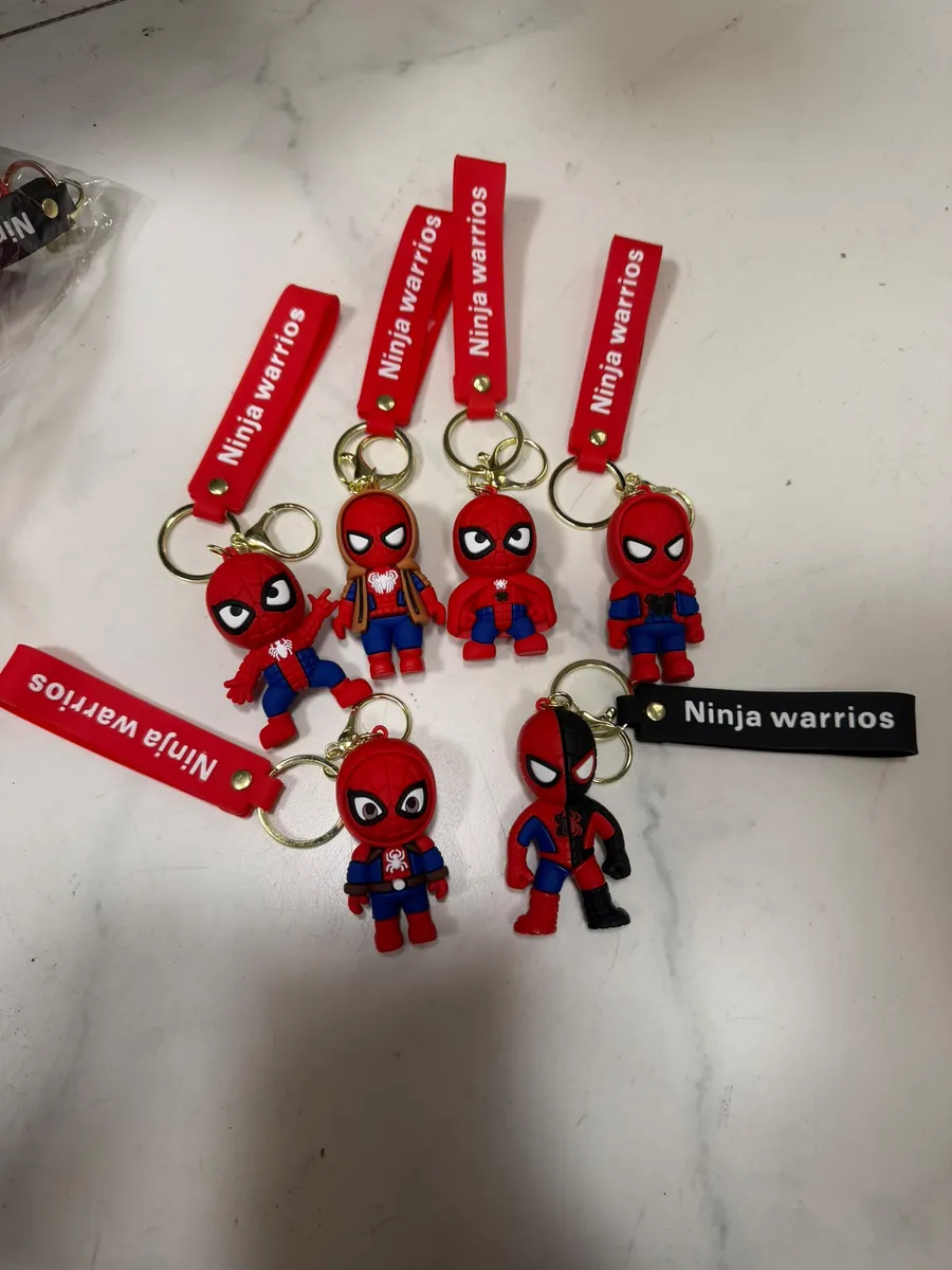 Zestaw breloków z czerwonym paskiem i figurkami Spidermana w różnych pozach na białym tle