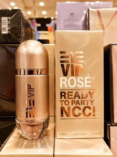 Butelka perfum VIP Rosé w kolorze różowego złota obok złotego pudełka z napisem