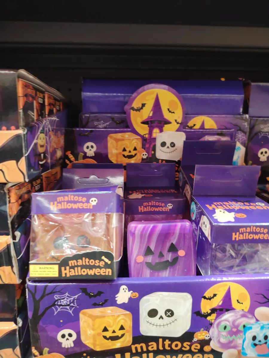Fioletowa kostka zabawka z motywem dyni w opakowaniu z napisem maltose Halloween
