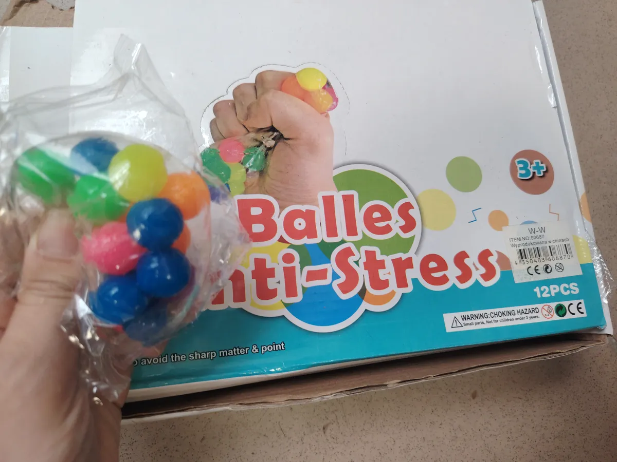 Kolorowe piłeczki sensoryczne w przezroczystym woreczku na tle opakowania z napisem Anti-Stress