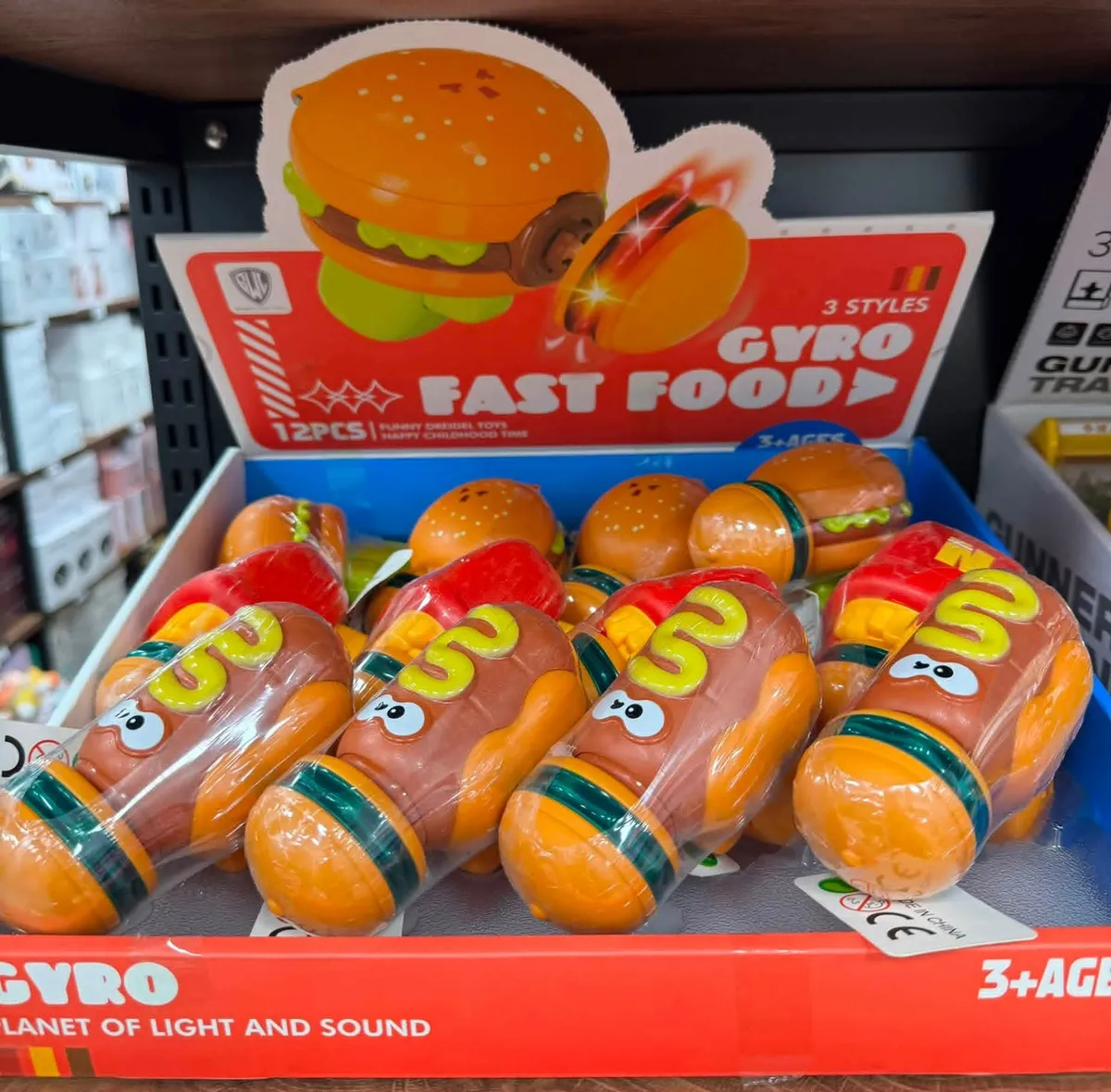 Zabawki Gyro Fast Food w kształcie hot doga w pomarańczowym kolorze z zielonymi i żółtymi detalami, opakowanie zbiorcze