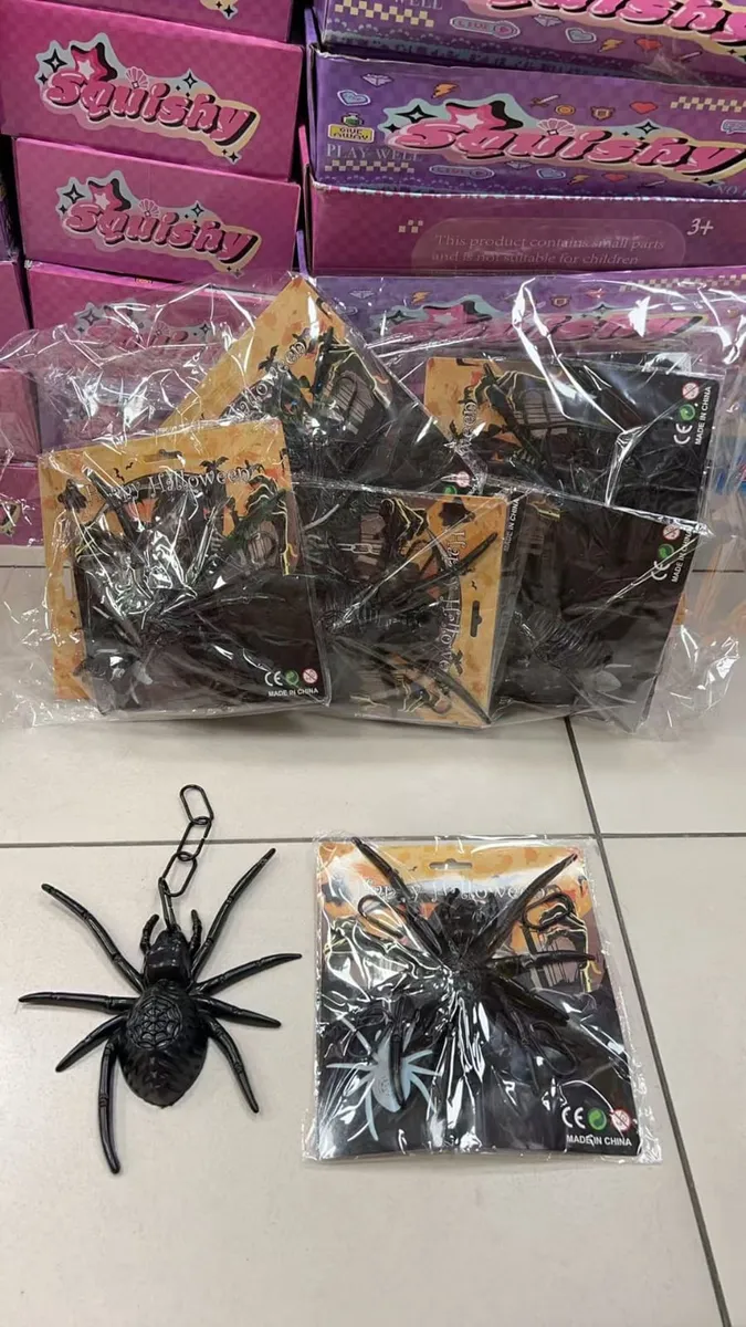 czarna plastikowa pajęczyna z łańcuszkiem na tle opakowań z motywem halloween