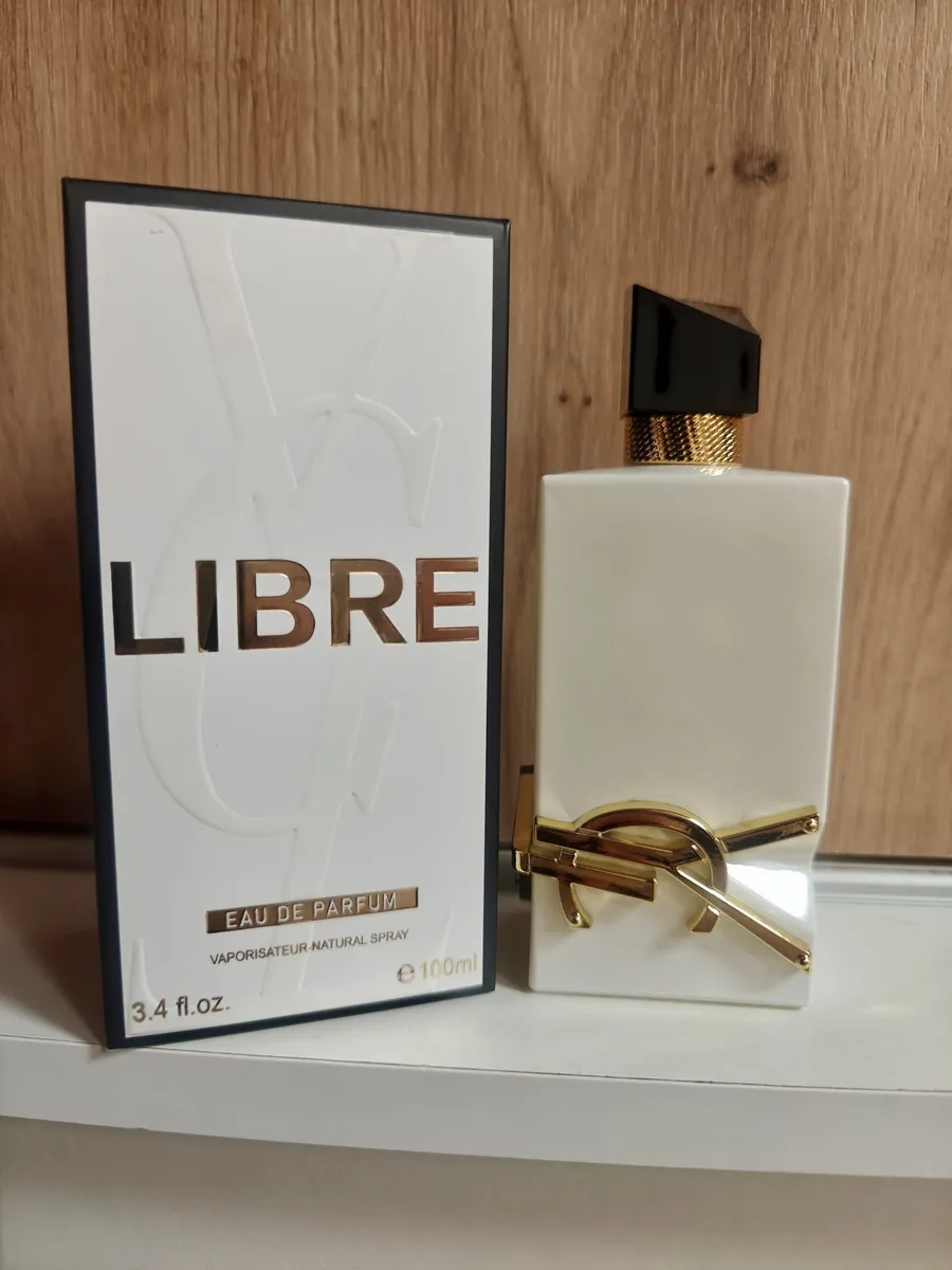 Biały flakon perfum Libre 100ml z czarną nakrętką i złotym logo obok białego pudełka z czarną ramką