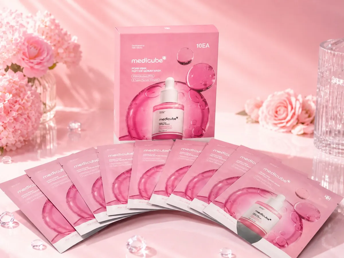 Różowe opakowanie Medicube PDRN Pink Peptide Serum Mask z 10 saszetkami na tle różowych kwiatów