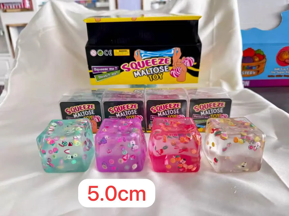 cztery przezroczyste kostki squeeze toy w kolorach zielonym, fioletowym, różowym i przezroczystym z kolorowymi elementami