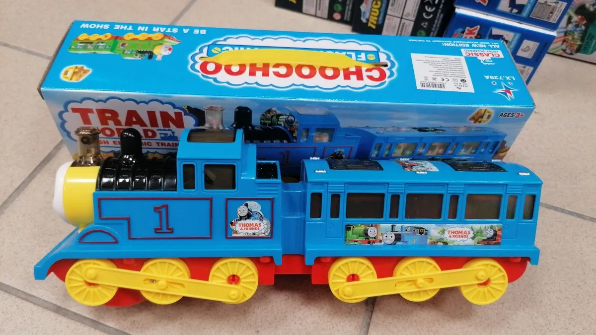 niebieska plastikowa lokomotywa zabawkowa z żółtymi kołami i naklejkami Thomas & Friends