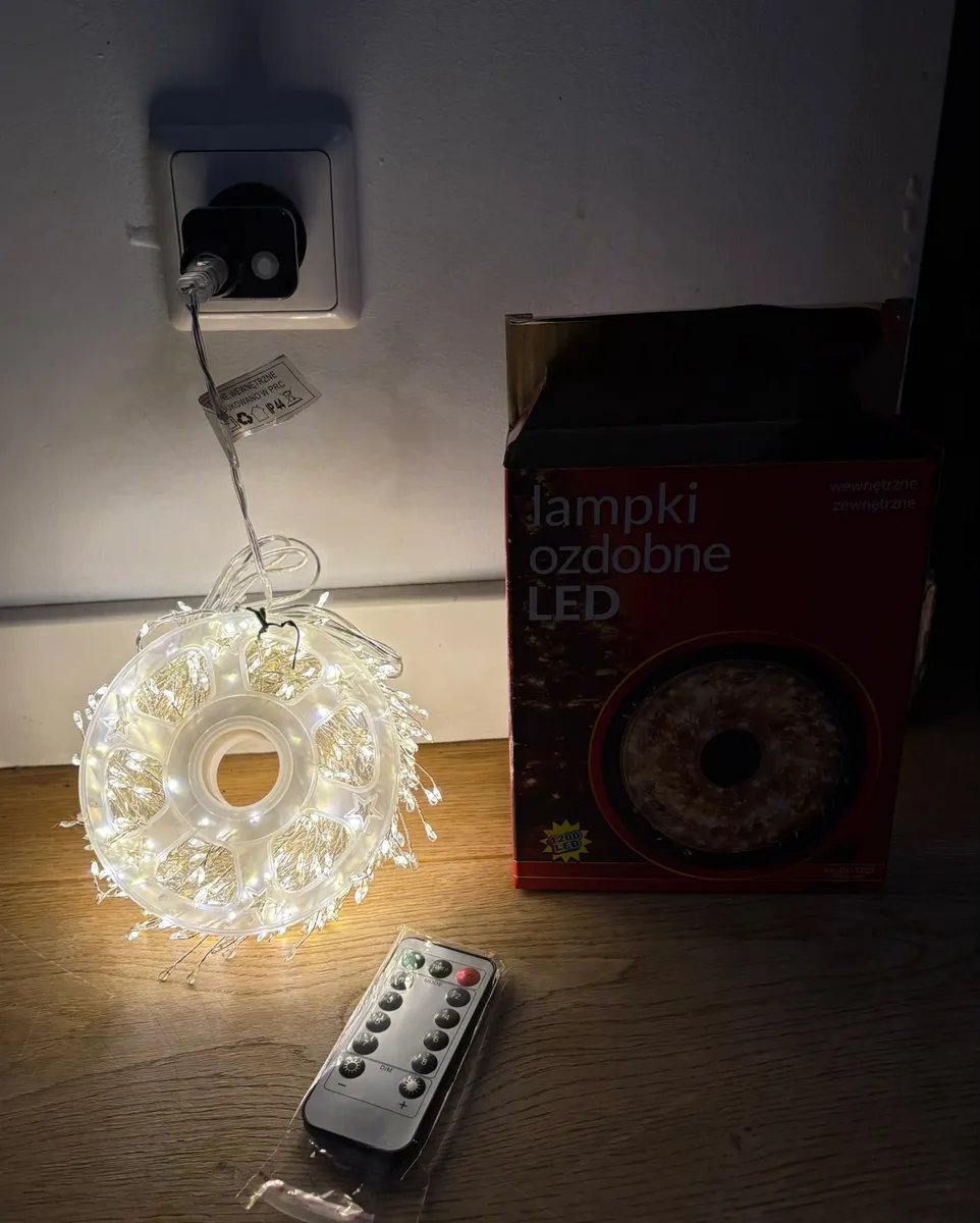 Lampki LED ciepły biały na cienkim druciku z pilotem i kartonem opakowania na drewnianej podłodze