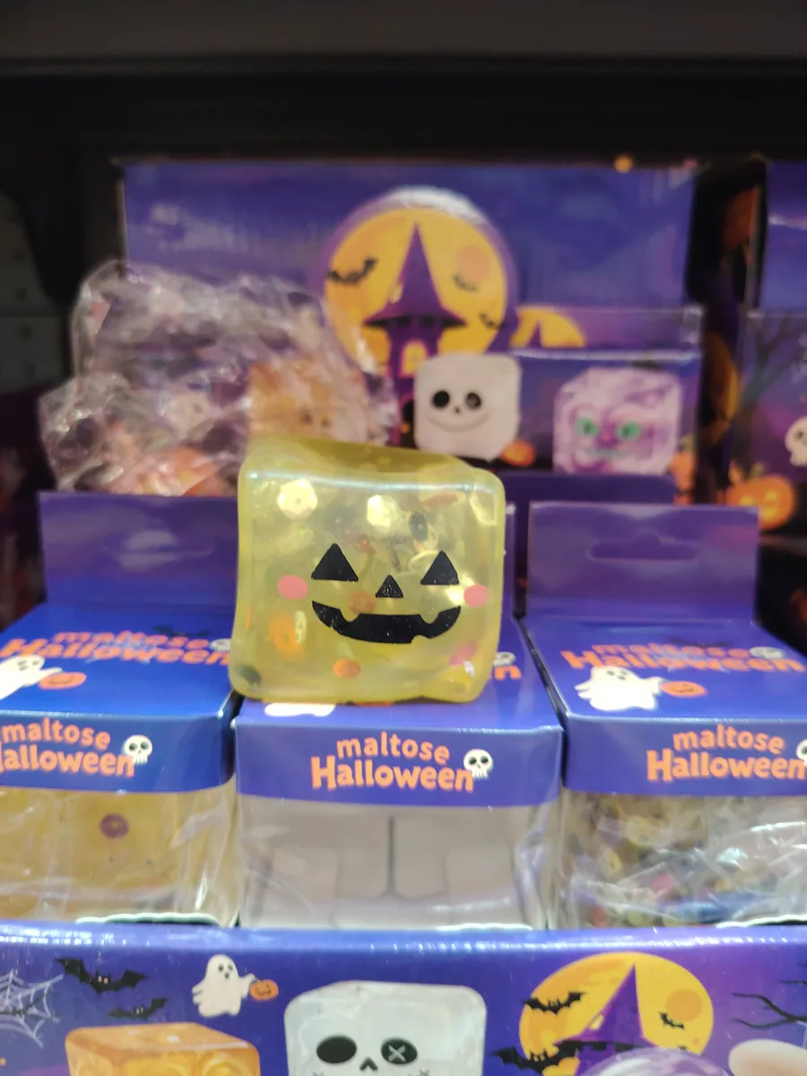 żółta żelowa kostka z nadrukiem uśmiechniętej dyni na granatowym opakowaniu z motywem Halloween