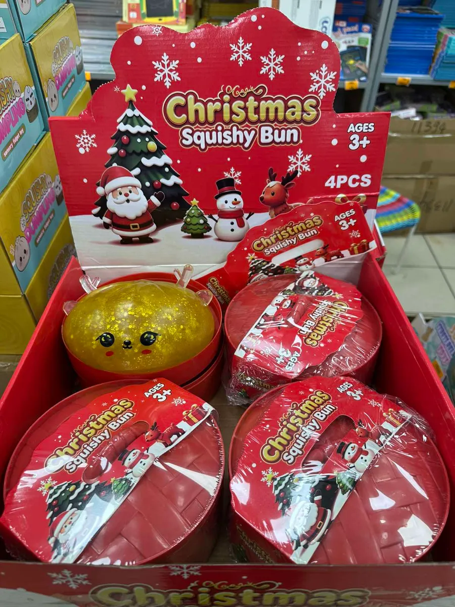 Czerwone opakowanie z motywem świątecznym i cztery zabawki squishy, jedna złota z brokatem i twarzą