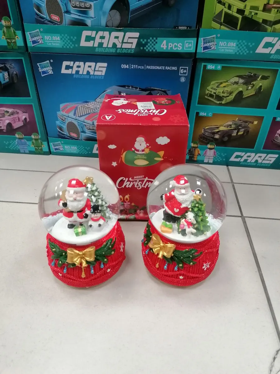 Dwie czerwone kule śnieżne z figurkami Mikołaja, choinki i prezentów na jasnym tle