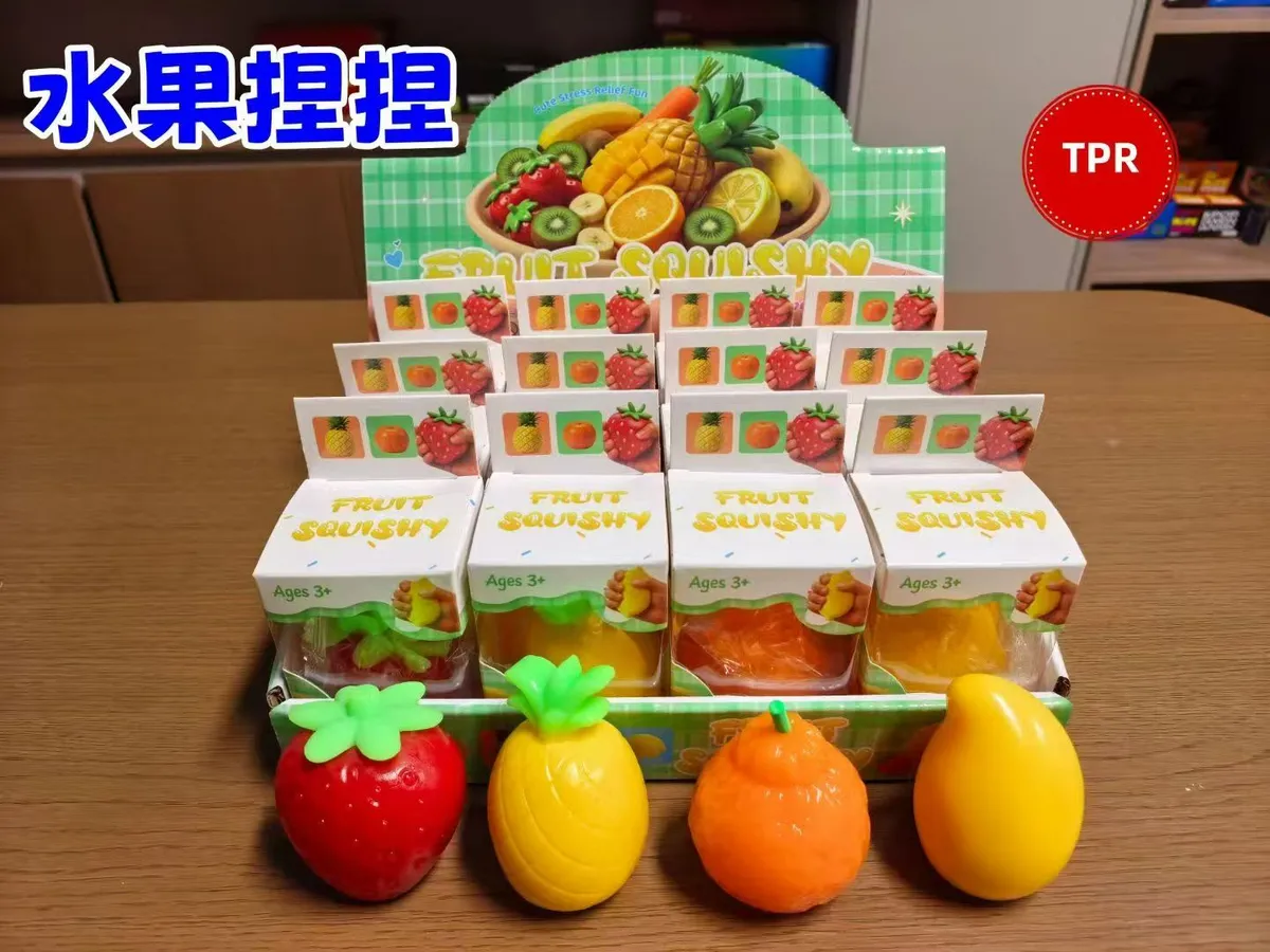 Zestaw czterech kolorowych gniotków antystresowych w kształcie truskawki, ananasa, pomarańczy i mango na stole
