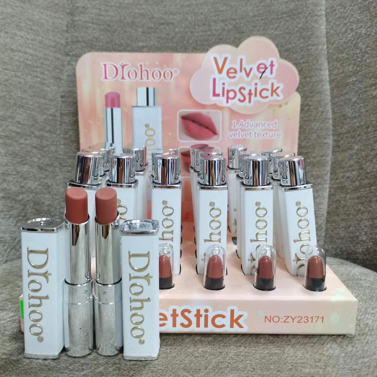 Pomadki Dłohoo Velvet Lipstick w białych opakowaniach z metalicznym srebrnym wykończeniem i beżowym kolorem sztyftu