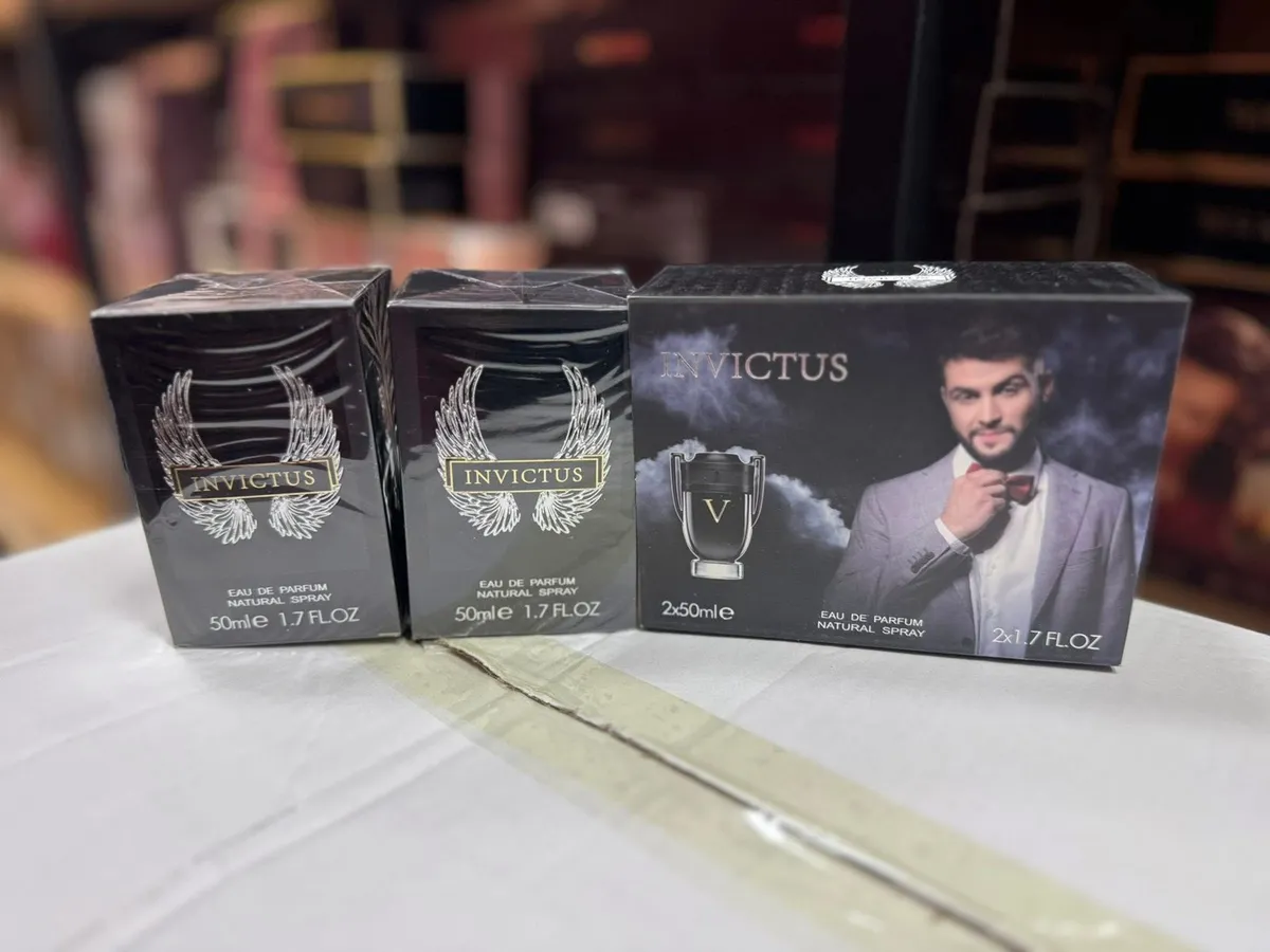 Zestaw dwóch czarnych butelek perfum Invictus 50ml oraz opakowanie z wizerunkiem mężczyzny w garniturze
