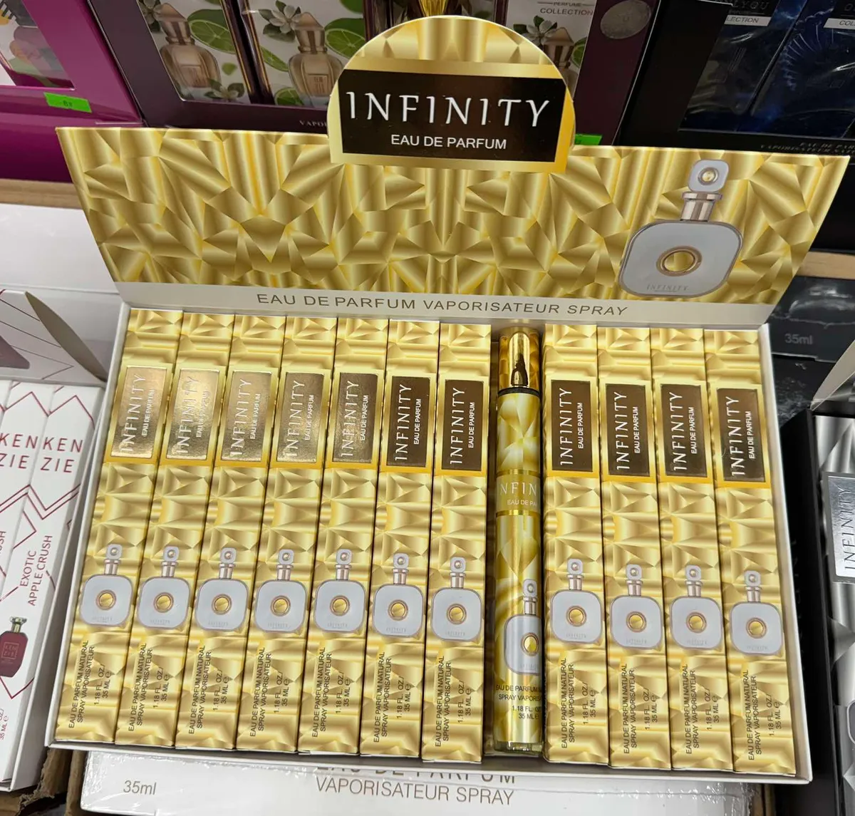 Złote opakowania perfum Infinity Eau de Parfum 35 ml w sprayu, ułożone w kartonie ekspozycyjnym